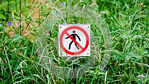 Red round prohibition sign with a black silhouette of a man crossed out. Prohibition to walk on the grass. Panoramic format