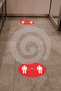 Red round sign printed on ground at supermarket cash desk register informing people to keep 2 meter 6 feet distance from