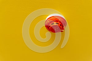 Red round smoke detectors provided on yellow ceiling background