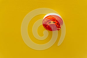 Red round smoke detectors provided on yellow ceiling background photo