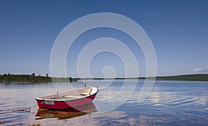 Red rowing boat on the shore of a lake