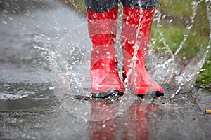 Red rubber boots are jumping into a big puddle photo
