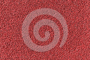 Red rubber pellets in treadmill athletics field texture abstract background