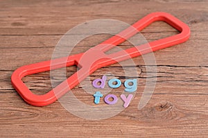 A red rubber tug of war toy for a dog with the word dog toy