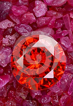 Red ruby on placed on a pile of raw granit gemstones.j