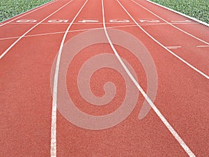 Red running track with lane numbers 1-6 and green grass in outdoor athletics stadium