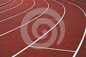 Red running track and white lanes on sport stadium.