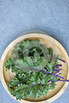 Red Russian Kale Leaves o Wooden Plate with Copy Space