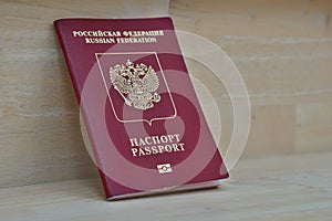 Red Russian passport on the wooden surface with captions Passport and Russian Federation in Cyrillic alphabet