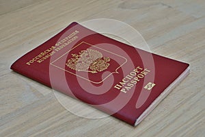 Red Russian passport on the wooden surface with captions Passport and Russian Federation in Cyrillic alphabet