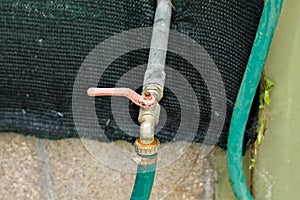 Red rusted handle of a garden tap with a green irrigator tube Italy, Europe