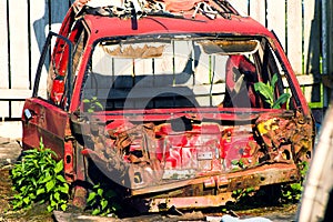 Red rusted and scraped car wreck.