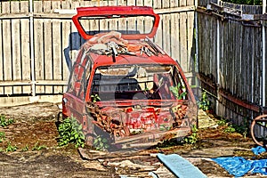 Red rusted and scraped car wreck.