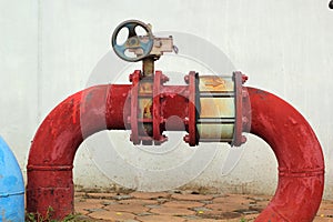 Red rusty metal industrial water pipes with a valve.