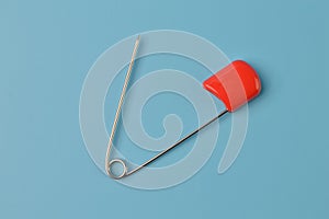 Red safety pin isolated on a blue background