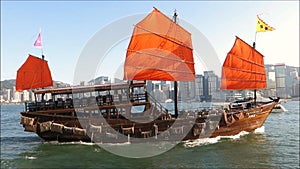 Red sail of the AquaLuna touring junk boat in Victoria harbor, Hong Kong