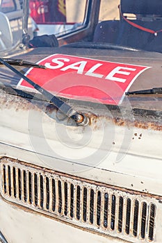 Red sale sign on grungy and old used car windshield, automobile
