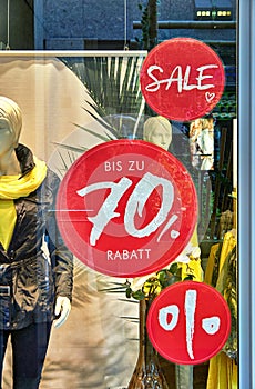 Red sale signs with mannequins in a clothing store in the background