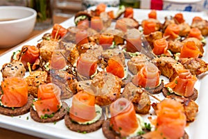 Red salmon appetizers on pumpernickel bread slices