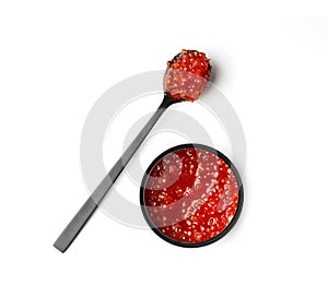 Red salmon caviar in a black tin can and black spoon on a white background
