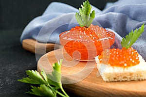 Red salmon caviar served with bread and parseley on wooden desk