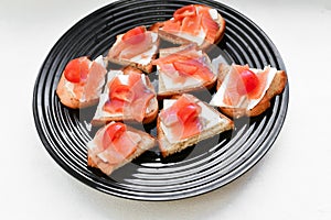 Red salmon on white bread. bagel and lox. view from above. black plate on a white background