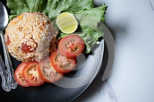 Red salted egg fried rice with vegetables in black plate