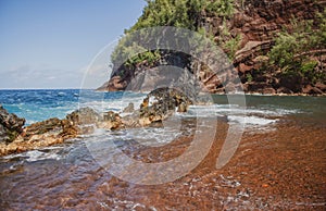 Red Sand Beach, Maui in in Hawaiian. Ocean waves and rock.