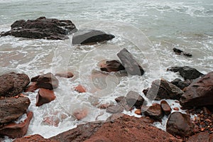 Red sand, stones, and rocks in Legzira Beach. Rugged coastline in the Tiznit Province of Morocco, Africa. Rough Atlantic Ocean