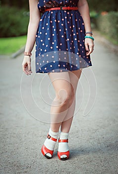 Red sandals with white socks on girl legs in fifties style