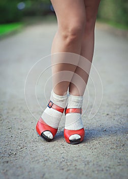 Red sandals with white socks on girl legs in fifties style