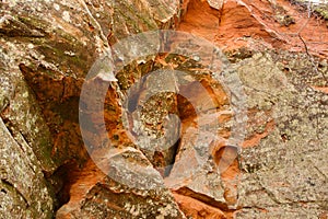 Red sandstone cliff with uneven surface. Limestone rock with cracks and slots