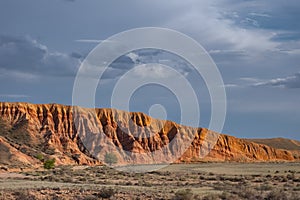 Red sandstone mountain formation with cloudy sky on background.