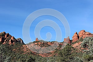 The red sandstone mountains of Sedona rising above the evergreen trees of Cococino National Forest