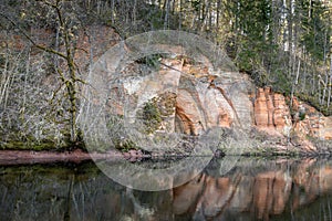 Red sandstones cliffs angel cave at the river Salaca