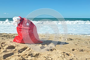 Red Santa bag with presents at the beach