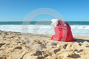 Red Santa bag with presents at the beach
