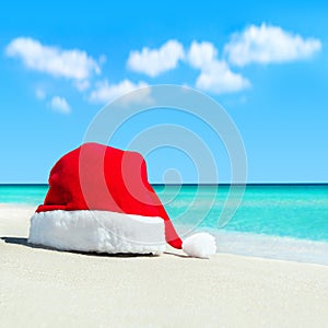 Red santa hat on white tropical beach sand - Christmas or New Ye
