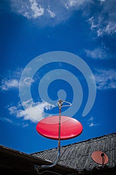 Red Satellite TV Receiver Dish on the Old Roof