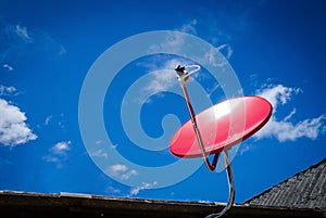 Red Satellite TV Receiver Dish on the Old Roof