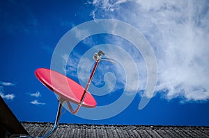 Red Satellite TV Receiver Dish on the Old Roof