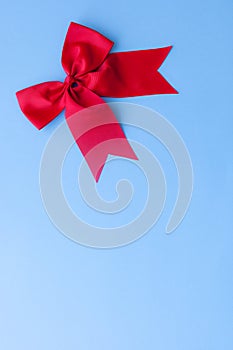 Red satin bow on pastel blue background with copy space/christmas card concept