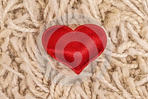 Red satin heart. Closeup on beige background