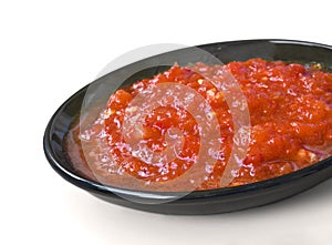 Red sauce on the black saucer isolated over white
