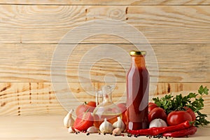 Red sauce in a bottle with ingredients, tomatoes, pepper and garlic on a natural wooden background. With space for inscripti