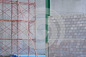 Red scaffolding with blue water pipes outside of industrial building structure in construction site area