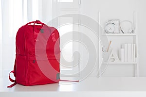 Red school backpack on table in children room interior