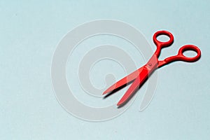 Red scissors on light blue background close up