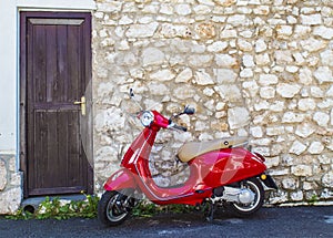 A red scooter in front of an old stone house