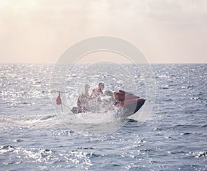 A red scooter rushing through the water, splashing spray